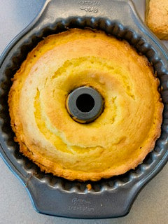 A freshly baked pound cake in a bundt pan, with a light golden color and a slightly cracked top.