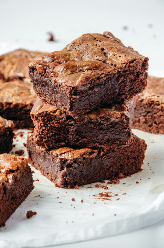 Thick, square fudge brownies with a deep chocolate color arranged neatly.